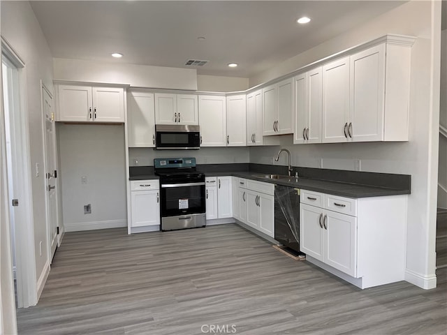 kitchen with white cabinets, stainless steel appliances, light wood-type flooring, and sink