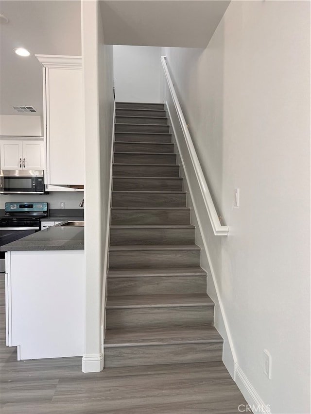 stairway with hardwood / wood-style flooring and sink