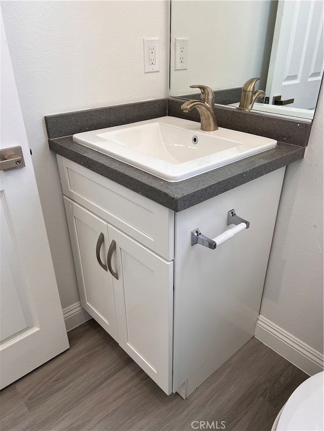 bathroom with wood-type flooring, vanity, and toilet