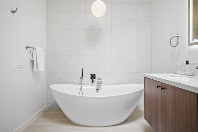 bathroom featuring a washtub, vanity, and tile walls