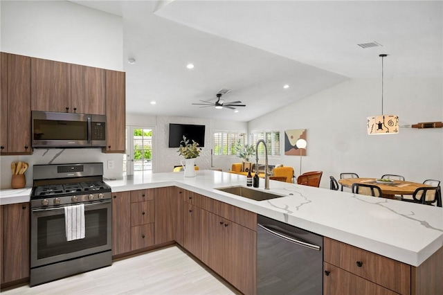 kitchen featuring appliances with stainless steel finishes, vaulted ceiling, ceiling fan, sink, and decorative light fixtures