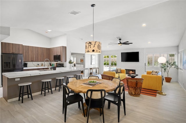 dining area featuring light hardwood / wood-style flooring, vaulted ceiling, ceiling fan, and sink