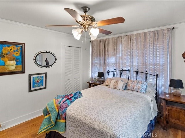 bedroom featuring hardwood / wood-style flooring, crown molding, ceiling fan, and a closet