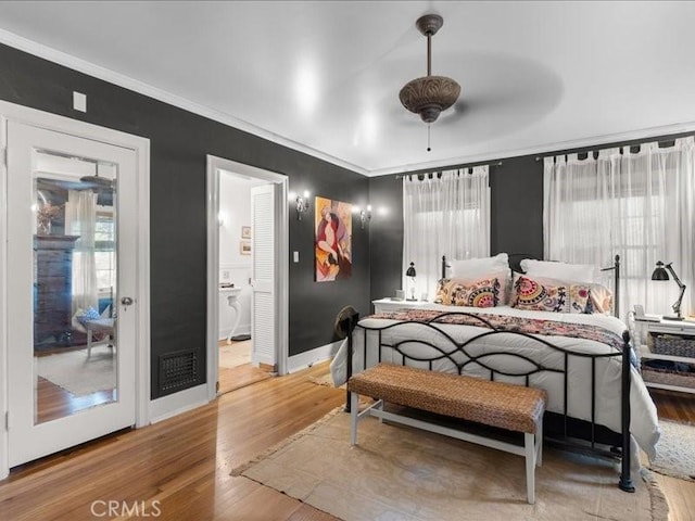 bedroom featuring multiple windows, crown molding, and wood-type flooring