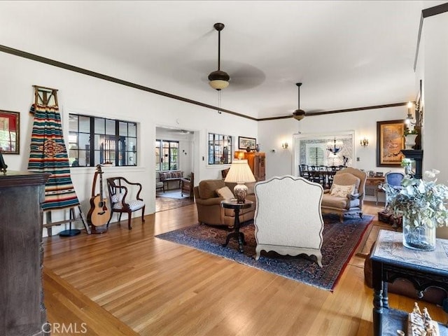 living room with hardwood / wood-style flooring, ceiling fan, and ornamental molding