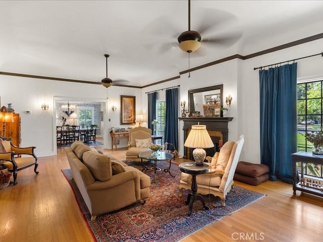 living room featuring light hardwood / wood-style flooring, ornamental molding, and ceiling fan