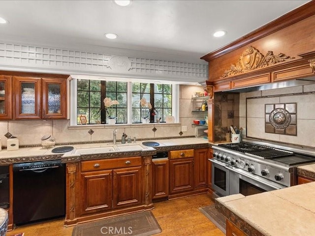 kitchen featuring range with two ovens, dishwasher, sink, and backsplash