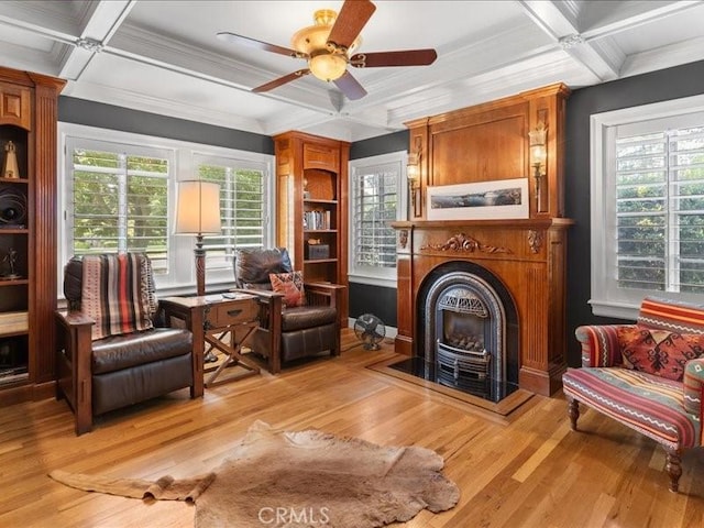 living area featuring beamed ceiling, coffered ceiling, ceiling fan, and light hardwood / wood-style flooring