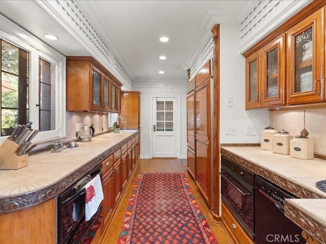 kitchen with sink, backsplash, light stone counters, black appliances, and crown molding