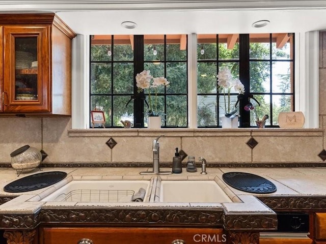 interior details featuring sink, light stone counters, and decorative backsplash