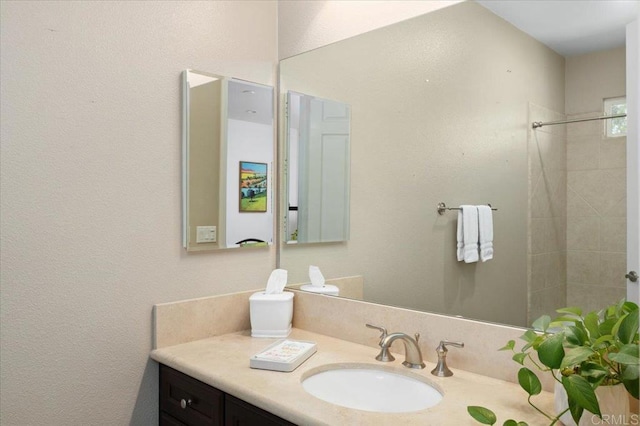 bathroom with a tile shower and vanity