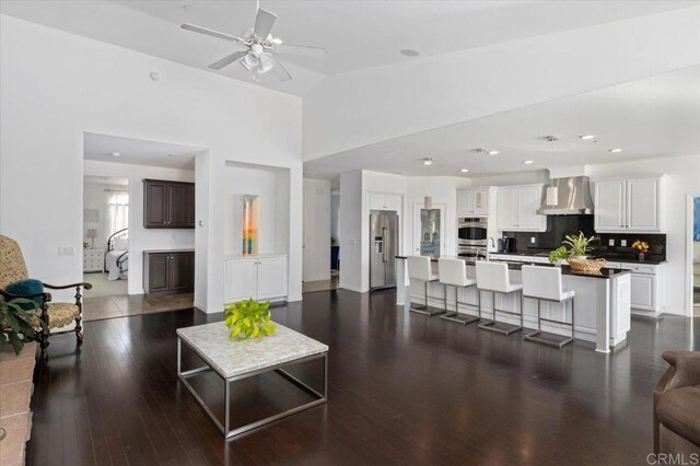 living room featuring dark wood-type flooring, high vaulted ceiling, and ceiling fan