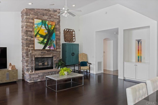 living room with ceiling fan, dark wood-type flooring, a fireplace, and vaulted ceiling