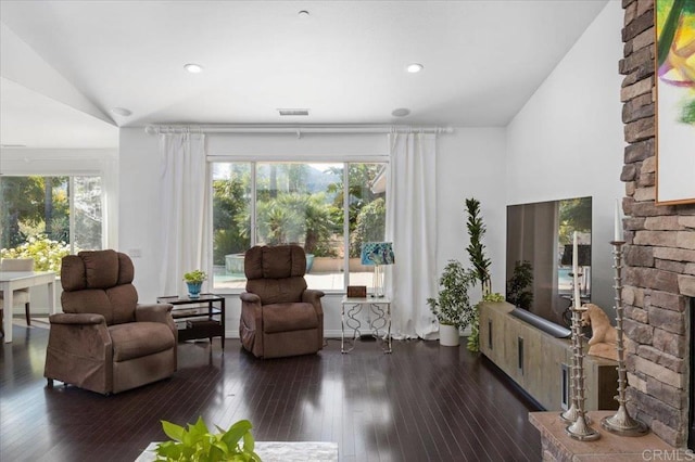 sitting room with a stone fireplace, vaulted ceiling, and dark hardwood / wood-style flooring