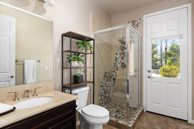 bathroom featuring a shower with door, vanity, and toilet