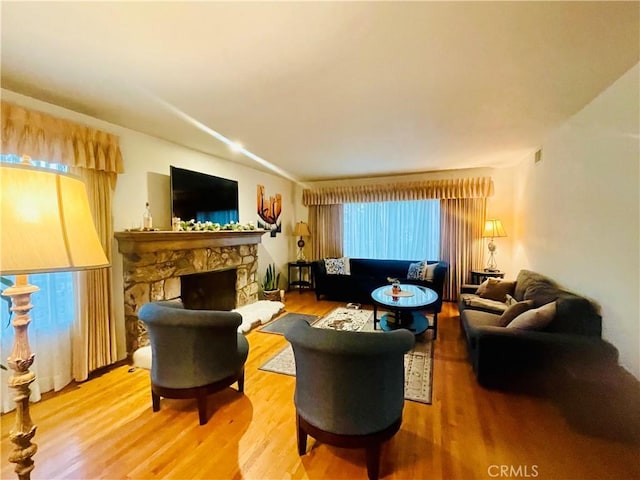 living room with a stone fireplace and hardwood / wood-style floors