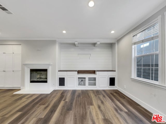 unfurnished living room featuring crown molding and dark hardwood / wood-style flooring