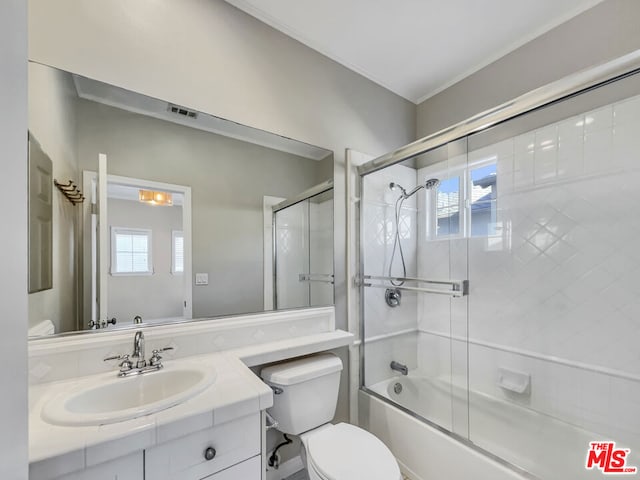 full bathroom with shower / bath combination with glass door, vanity, toilet, and a wealth of natural light