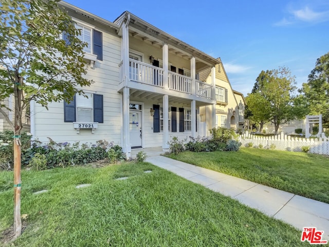 view of front of property with a balcony and a front lawn