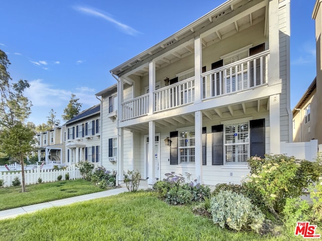 view of front of house featuring a balcony and a front lawn