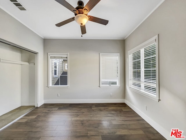 unfurnished bedroom with a closet, dark hardwood / wood-style floors, ceiling fan, and crown molding