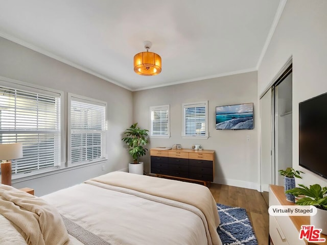 bedroom featuring wood-type flooring, ornamental molding, and a closet