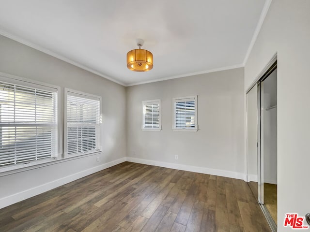 unfurnished bedroom with crown molding, a closet, and dark hardwood / wood-style floors