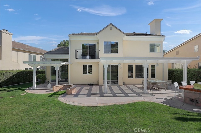 back of house featuring a balcony, a pergola, a patio area, and a lawn