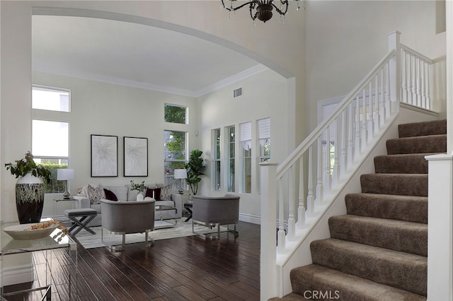 living room with ornamental molding, wood-type flooring, a notable chandelier, and a high ceiling