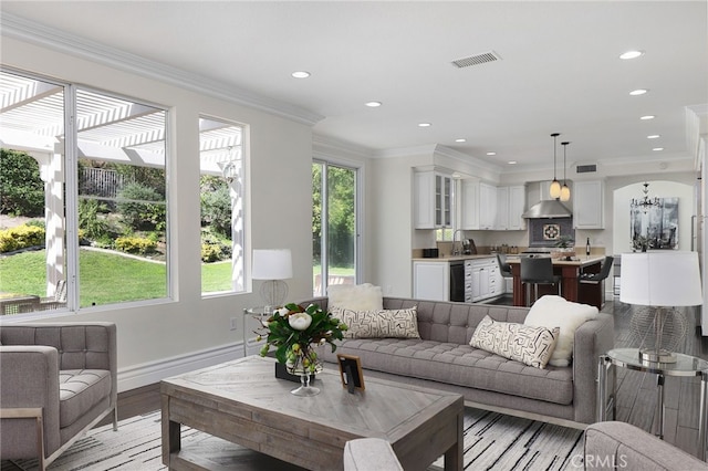 living room with sink, ornamental molding, and light wood-type flooring