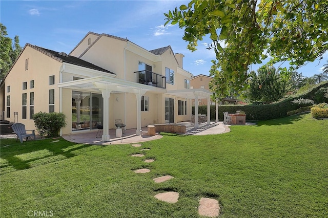 rear view of house featuring a pergola, a patio area, a balcony, and a lawn