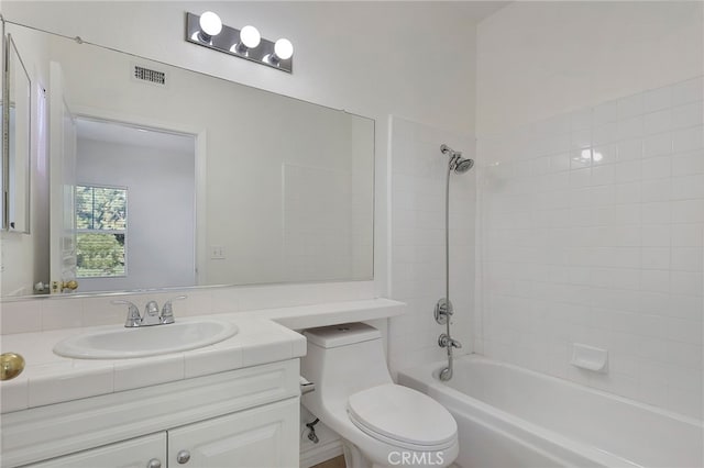 full bathroom featuring tiled shower / bath, vanity, and toilet