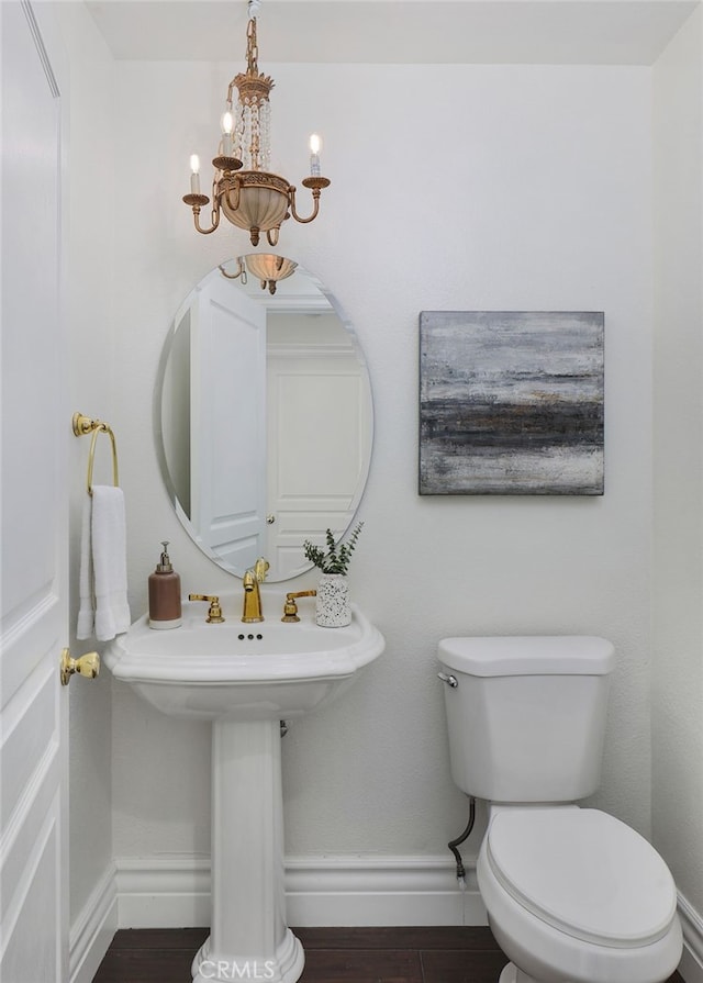 bathroom with an inviting chandelier, wood-type flooring, and toilet