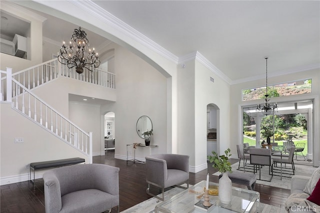 living room with a high ceiling, ornamental molding, dark hardwood / wood-style floors, and an inviting chandelier