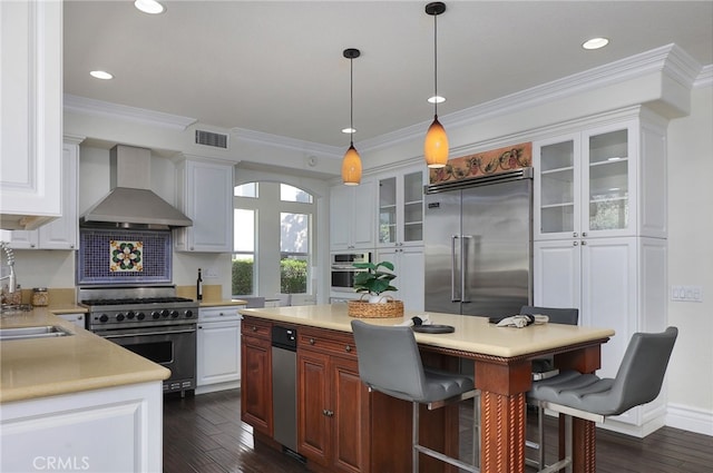 kitchen featuring white cabinetry, wall chimney exhaust hood, a kitchen island, and premium appliances