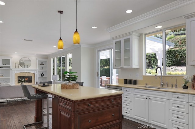 kitchen featuring a breakfast bar, pendant lighting, sink, white cabinets, and crown molding