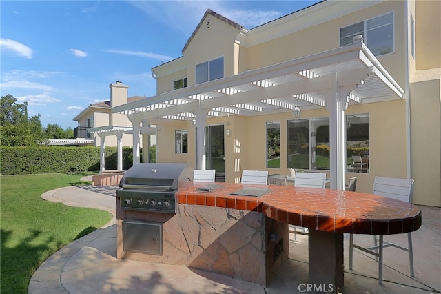 rear view of property with exterior kitchen, a yard, a pergola, and a patio area