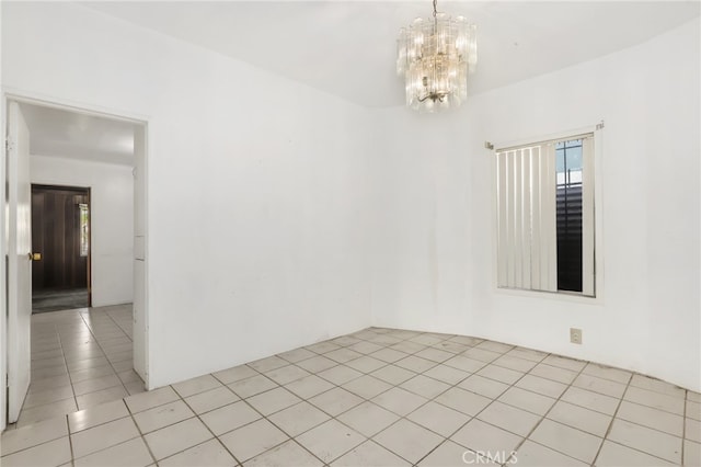 spare room featuring light tile patterned floors, an inviting chandelier, and a wealth of natural light