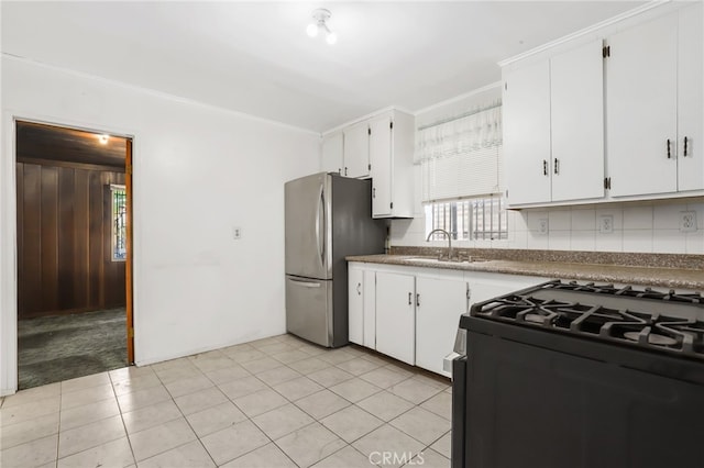 kitchen with stainless steel fridge, black range with gas stovetop, decorative backsplash, ornamental molding, and white cabinets