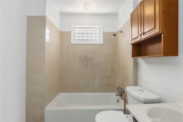 full bathroom featuring tiled shower / bath, vanity, and toilet