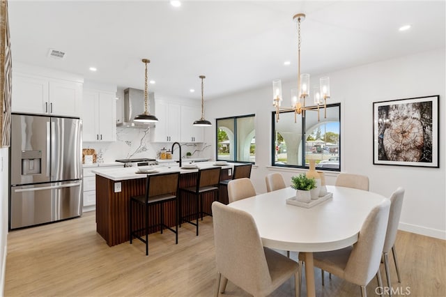 dining space with a notable chandelier and light hardwood / wood-style flooring