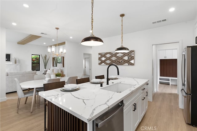 kitchen featuring a kitchen island with sink, light wood-type flooring, sink, appliances with stainless steel finishes, and white cabinetry