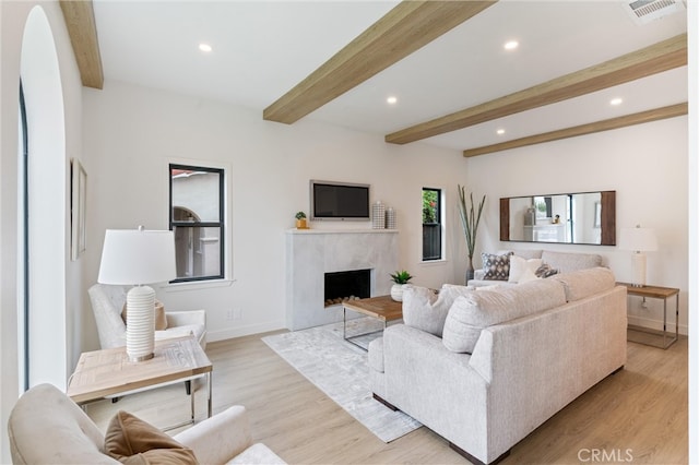 living room featuring light hardwood / wood-style floors, beam ceiling, and a high end fireplace