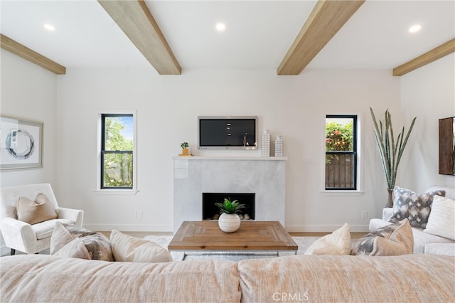 living room featuring plenty of natural light, beamed ceiling, and a premium fireplace