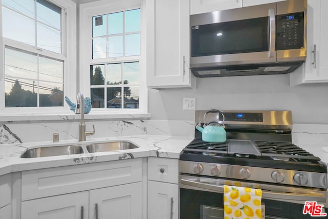 kitchen featuring stainless steel appliances, plenty of natural light, sink, and white cabinetry