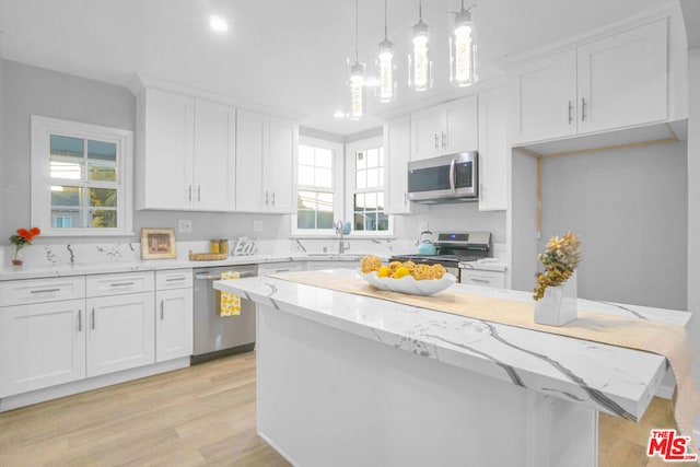 kitchen featuring plenty of natural light, hanging light fixtures, stainless steel appliances, and white cabinets