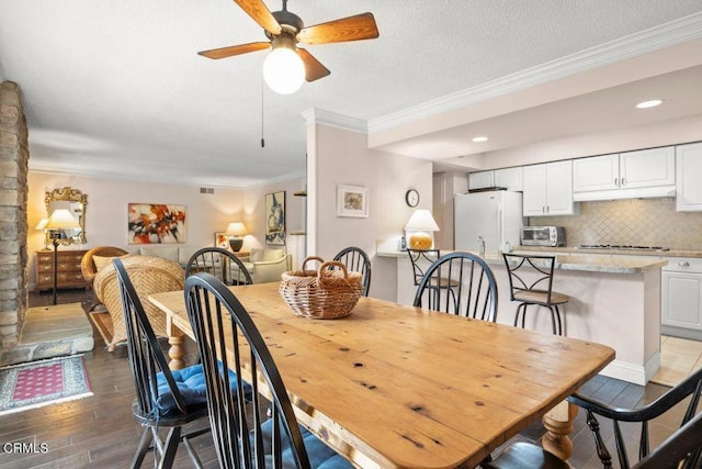 dining room with dark hardwood / wood-style flooring, a textured ceiling, ornamental molding, and ceiling fan