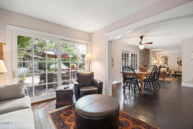 living room with ceiling fan, a textured ceiling, and dark hardwood / wood-style floors