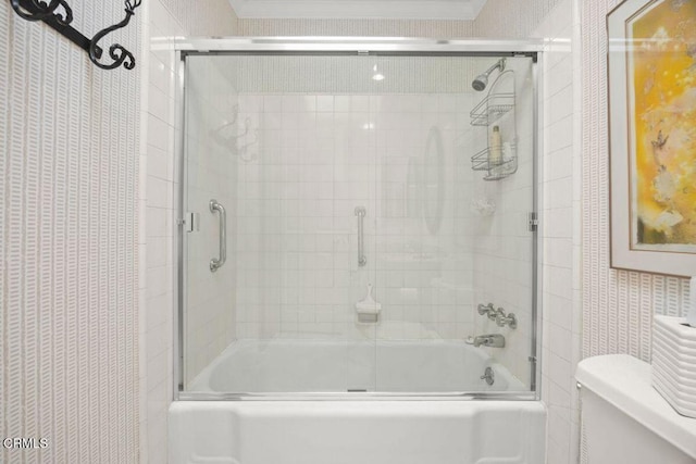 bathroom featuring toilet and bath / shower combo with glass door