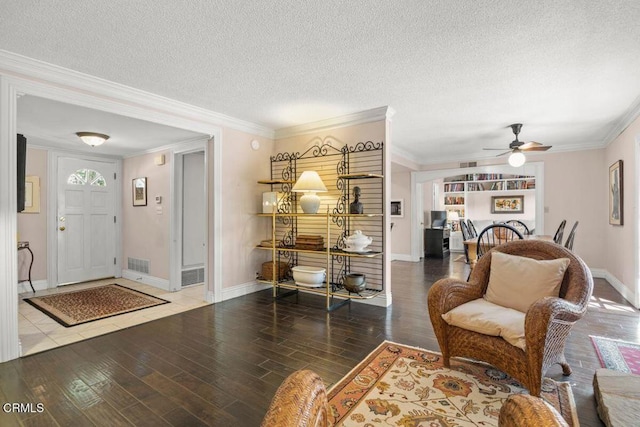 living area with hardwood / wood-style flooring, a textured ceiling, ceiling fan, and crown molding